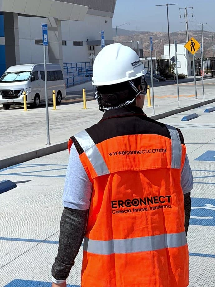 Técnico de ERCONNECT con casco y chaleco de seguridad llegando a una obra industrial