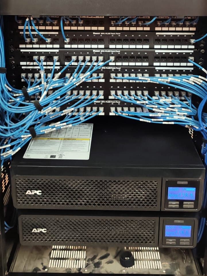 Fotografía de obra con un IDF ordenado y dos UPS de rack APC en la parte baja del gabinete