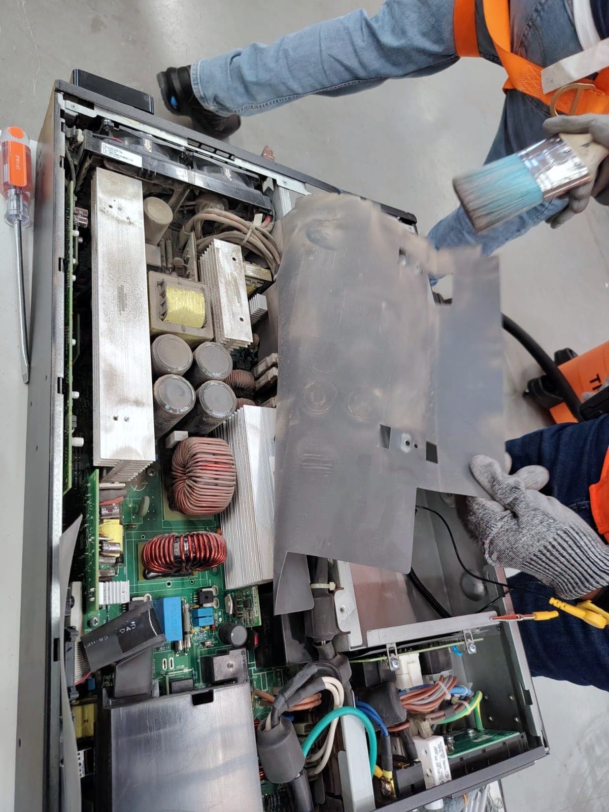Fotografía del proyecto con un UPS de rack abierto sobre la mesa de trabajo mientras un técnico limpia sus componentes internos con brocha
