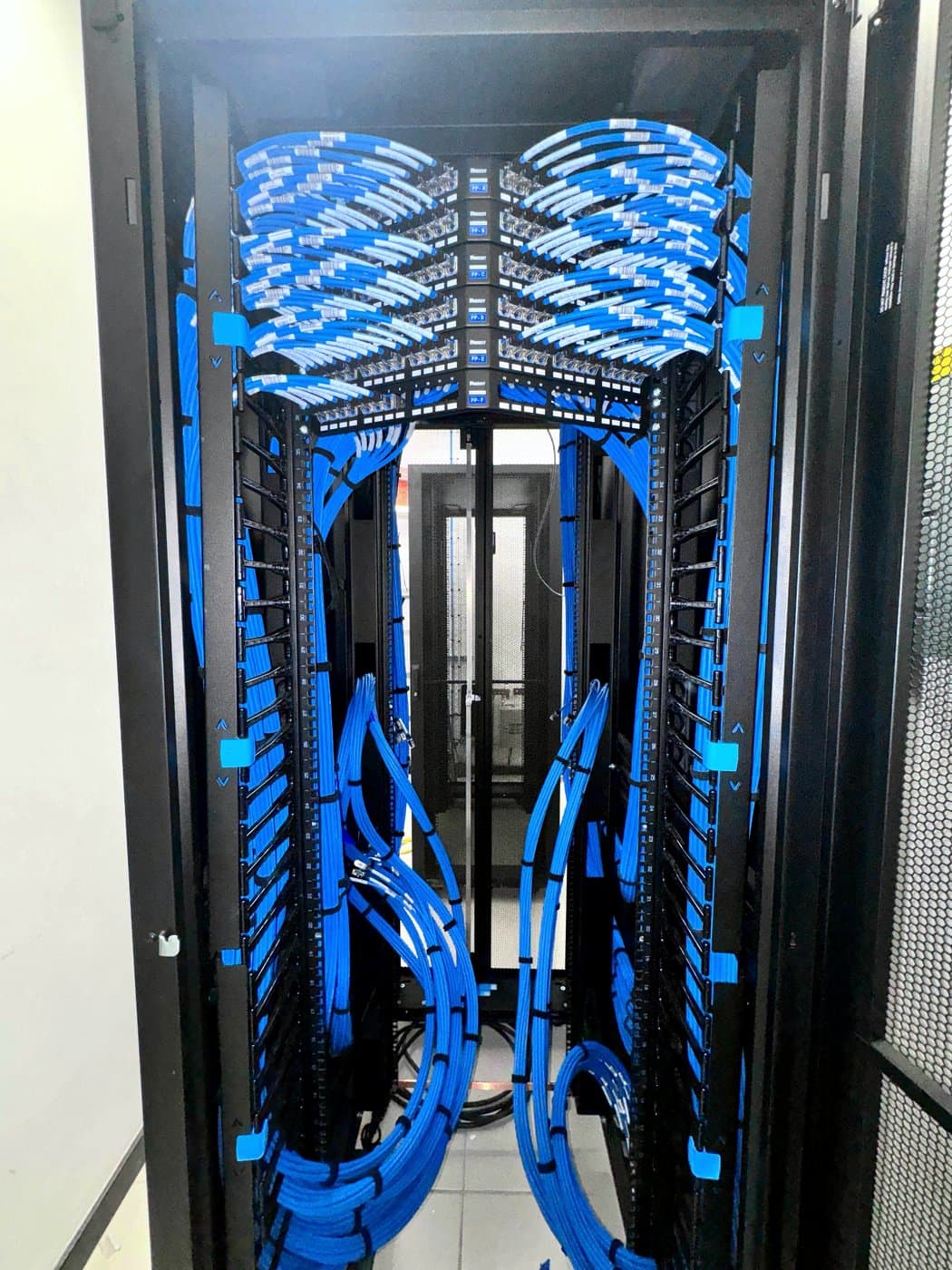 Fotografía del proyecto que muestra el interior del rack con cableado azul administrado simétricamente hacia los paneles de parcheo