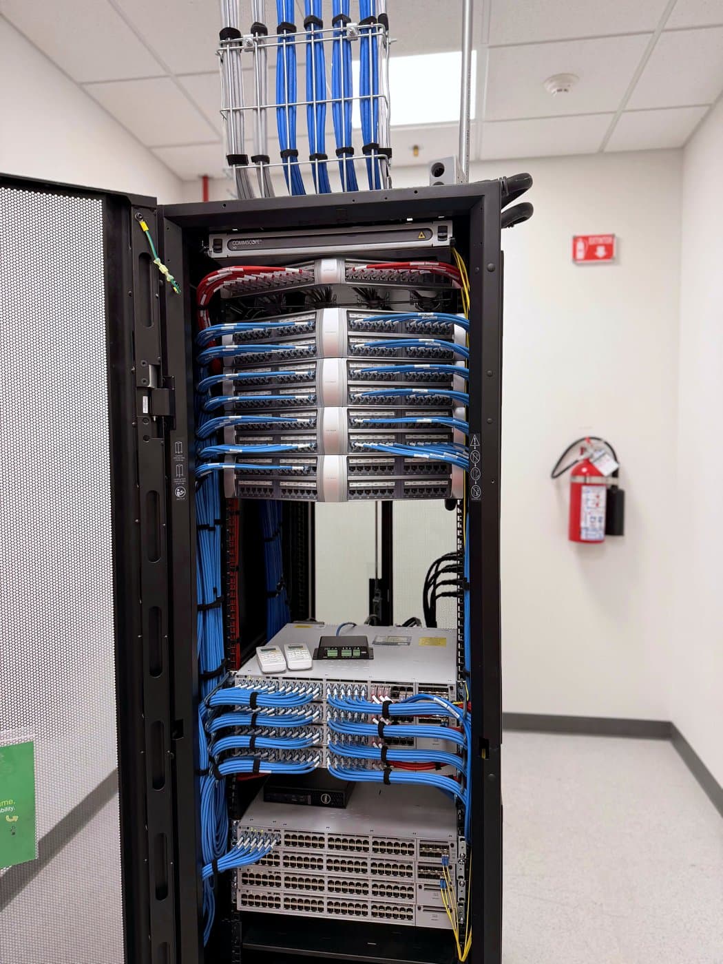 Fotografía de instalación ERCONNECT: rack con switches y paneles de parcheo con cableado azul organizado